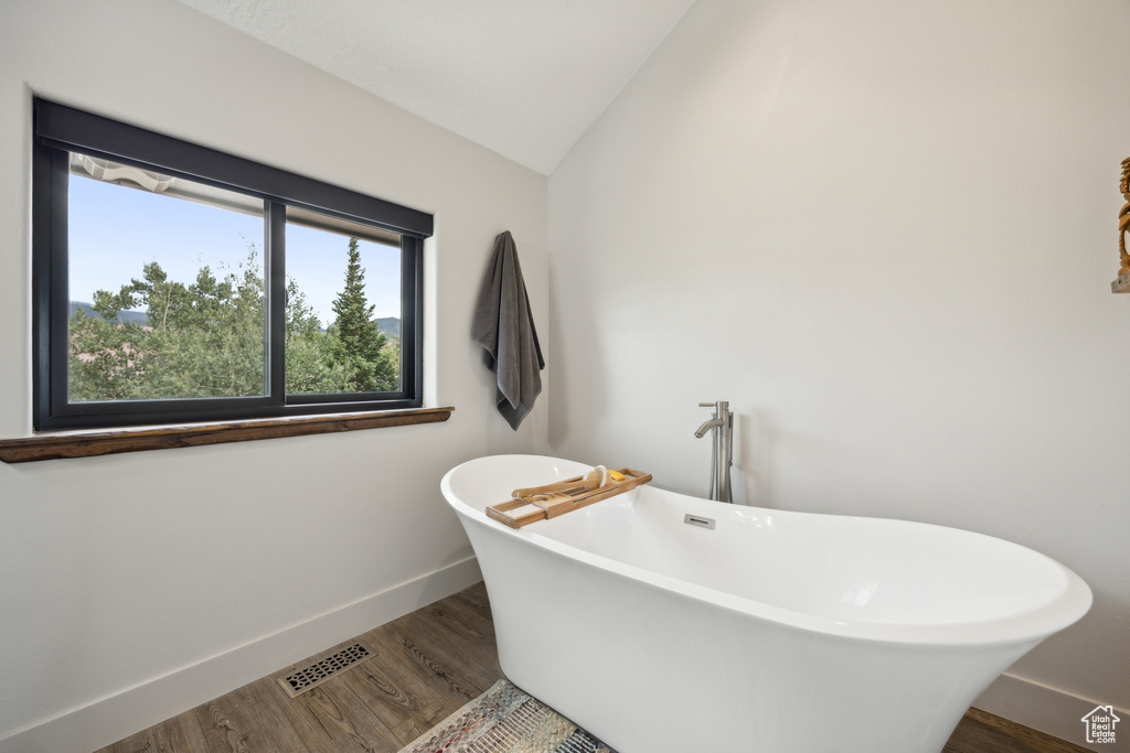 Bathroom with lofted ceiling, hardwood / wood-style floors, and a bathtub