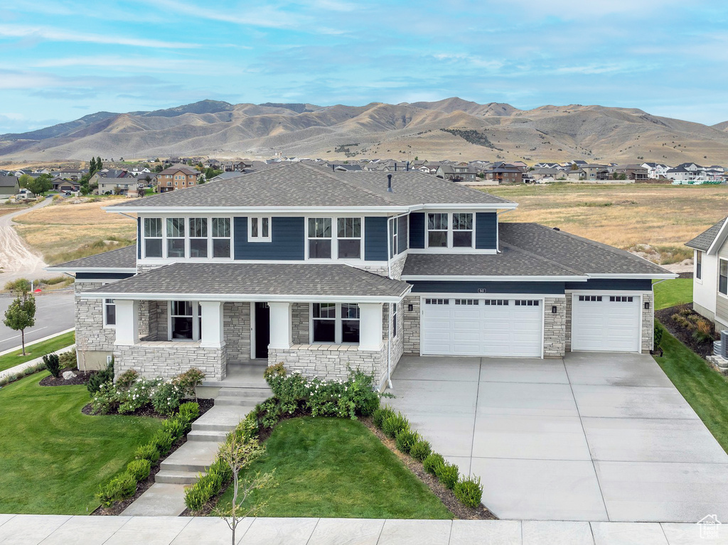 View of front of house featuring a garage, a front lawn, and a mountain view