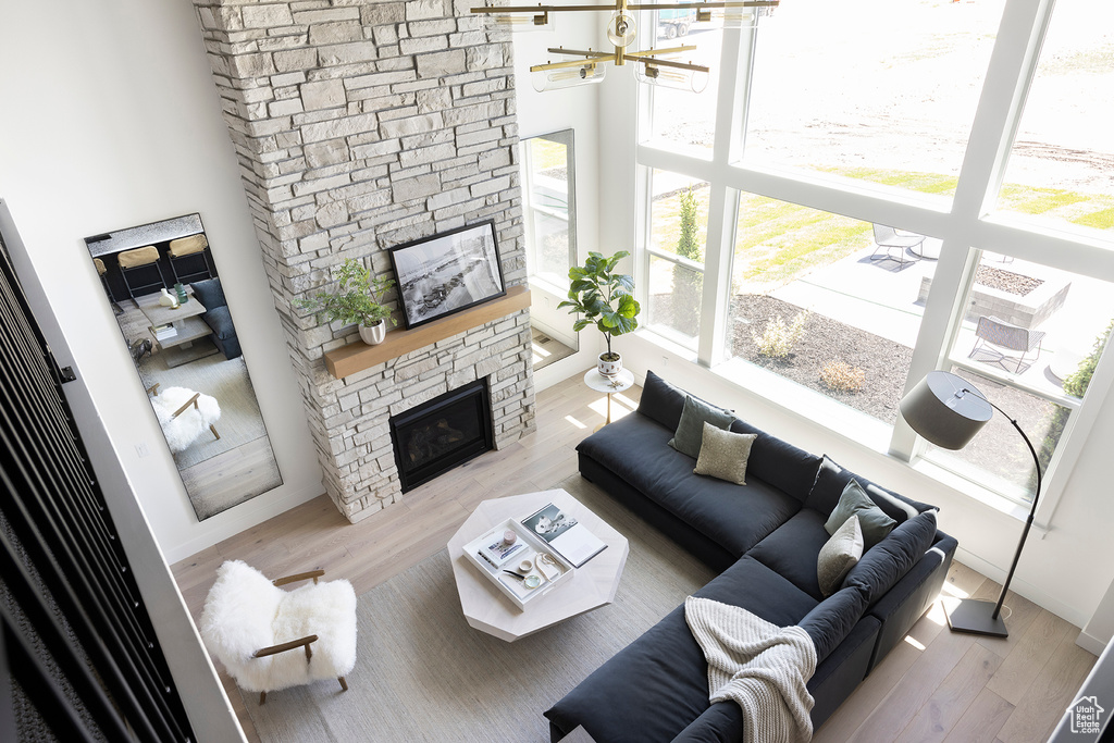 Living room with a healthy amount of sunlight, wood-type flooring, a stone fireplace, and a high ceiling