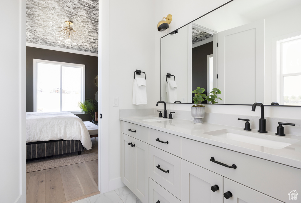 Bathroom with a healthy amount of sunlight, ornamental molding, dual vanity, and hardwood / wood-style flooring