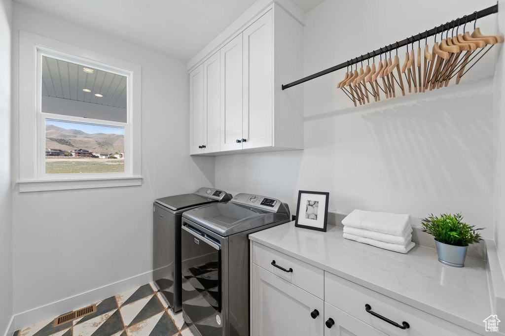 Laundry room with tile flooring, cabinets, and independent washer and dryer