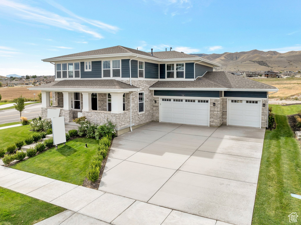 View of front of property with a mountain view, a front yard, a porch, and a garage