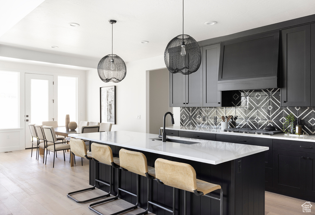 Kitchen with plenty of natural light, stainless steel gas stovetop, light wood-type flooring, sink, and a kitchen island with sink