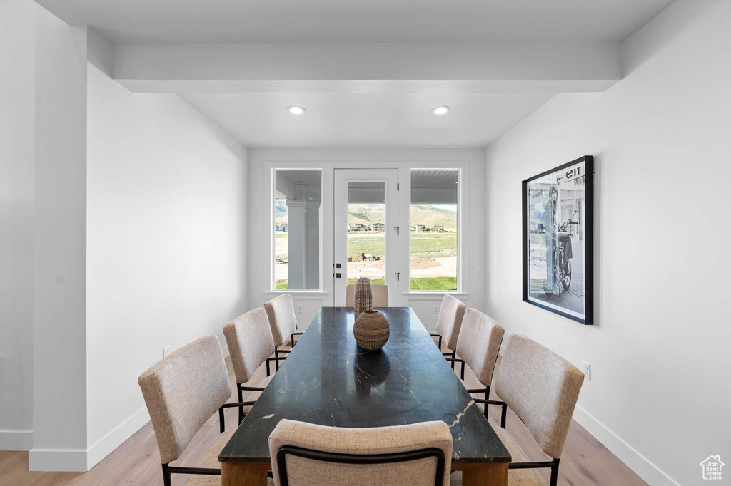 Dining area with beam ceiling and light hardwood / wood-style floors