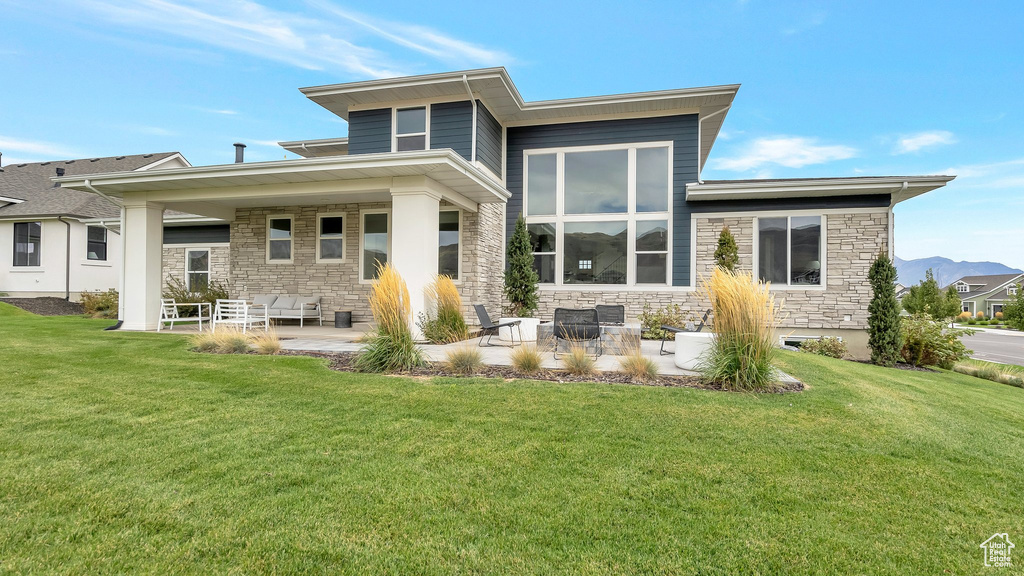 Rear view of property featuring a lawn and a patio area