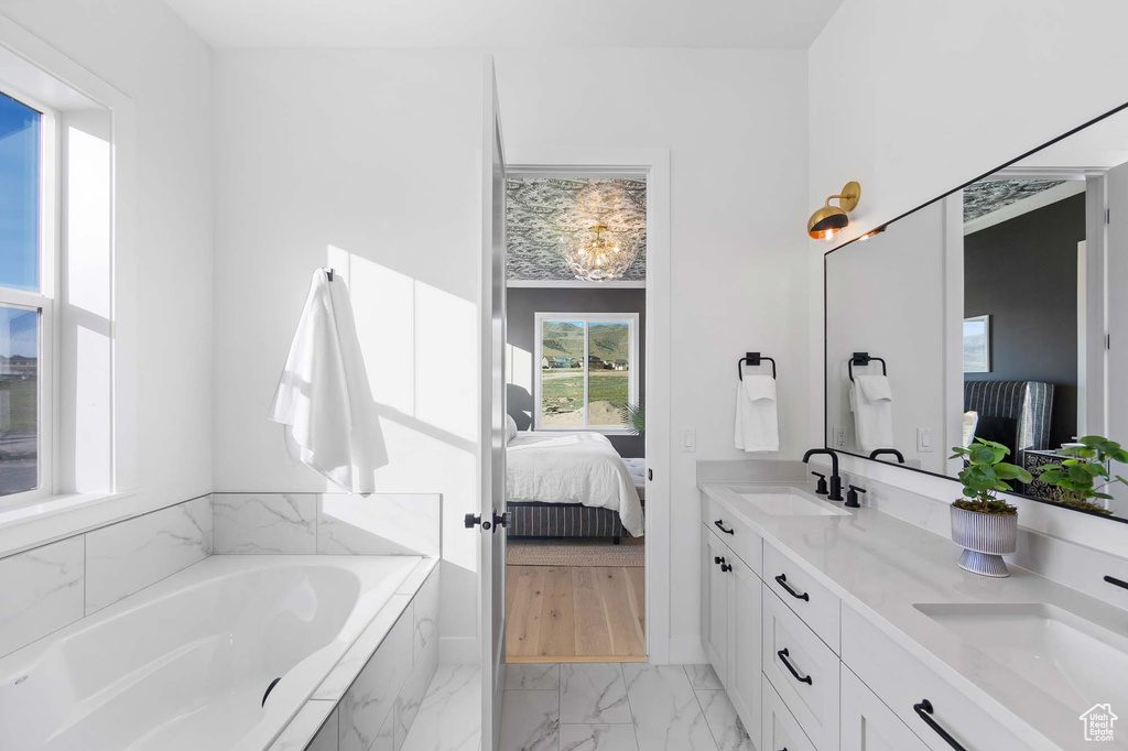 Bathroom featuring a relaxing tiled bath, tile flooring, double sink, and large vanity