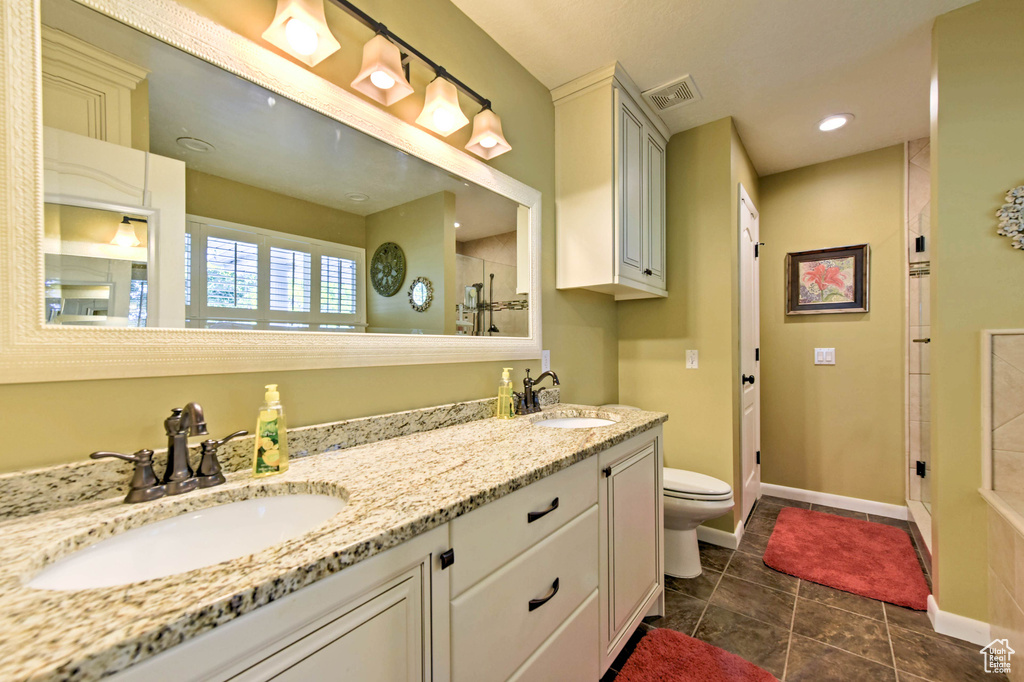 Bathroom with walk in shower, tile patterned flooring, toilet, and double sink vanity