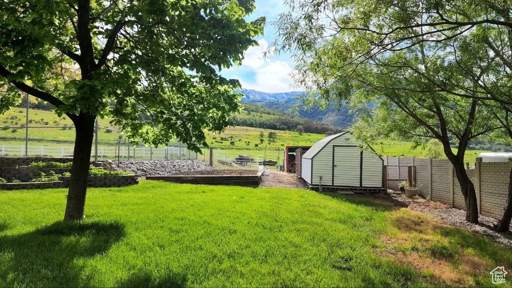 View of yard featuring a mountain view, a rural view, and a shed