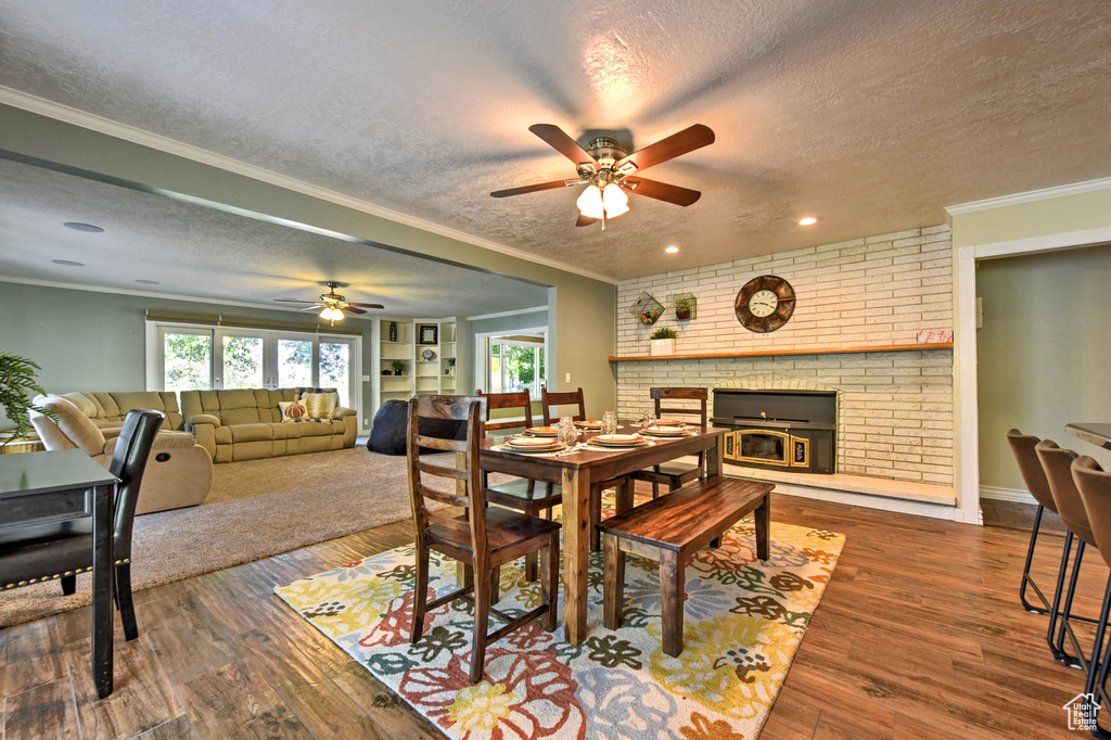 Dining room with a textured ceiling, ornamental molding, a fireplace, and dark hardwood / wood-style floors