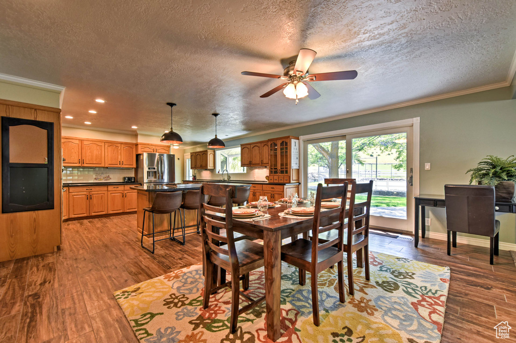 Dining room featuring wood-type flooring, crown molding, sink, and ceiling fan