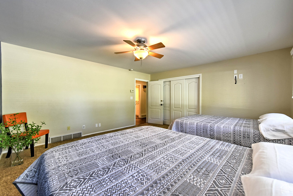 Carpeted bedroom with ceiling fan and a closet