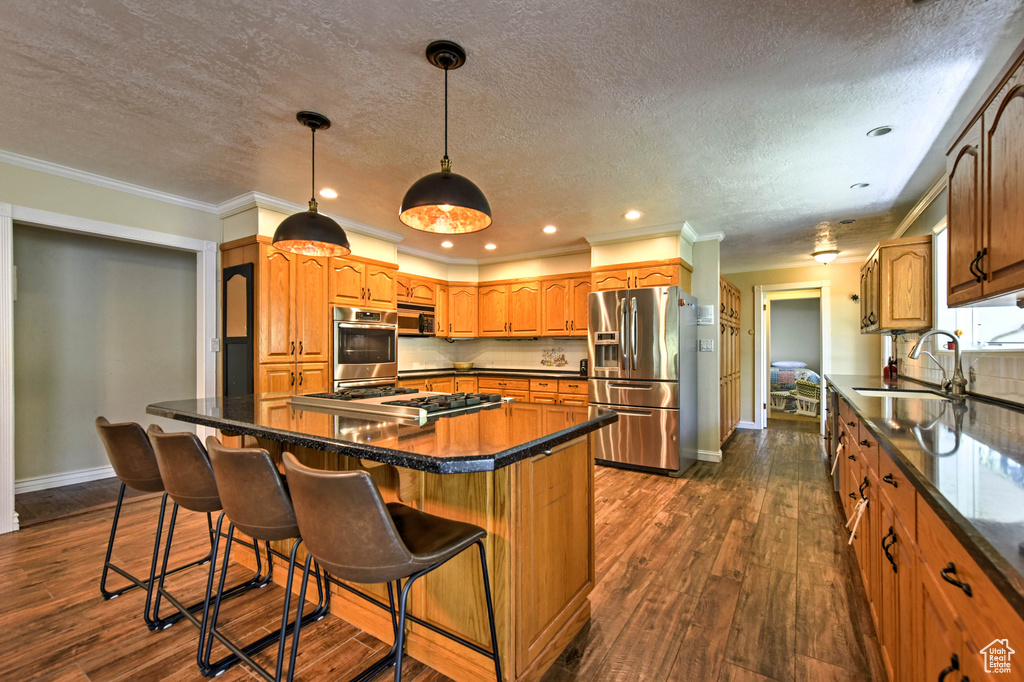 Kitchen featuring a center island, appliances with stainless steel finishes, dark hardwood / wood-style floors, and a breakfast bar area