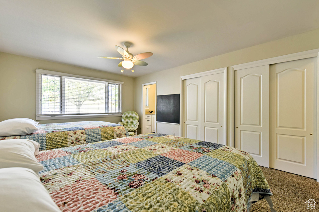 Carpeted bedroom with multiple closets and ceiling fan