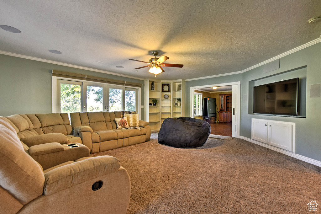 Carpeted living room featuring ornamental molding, a textured ceiling, and ceiling fan