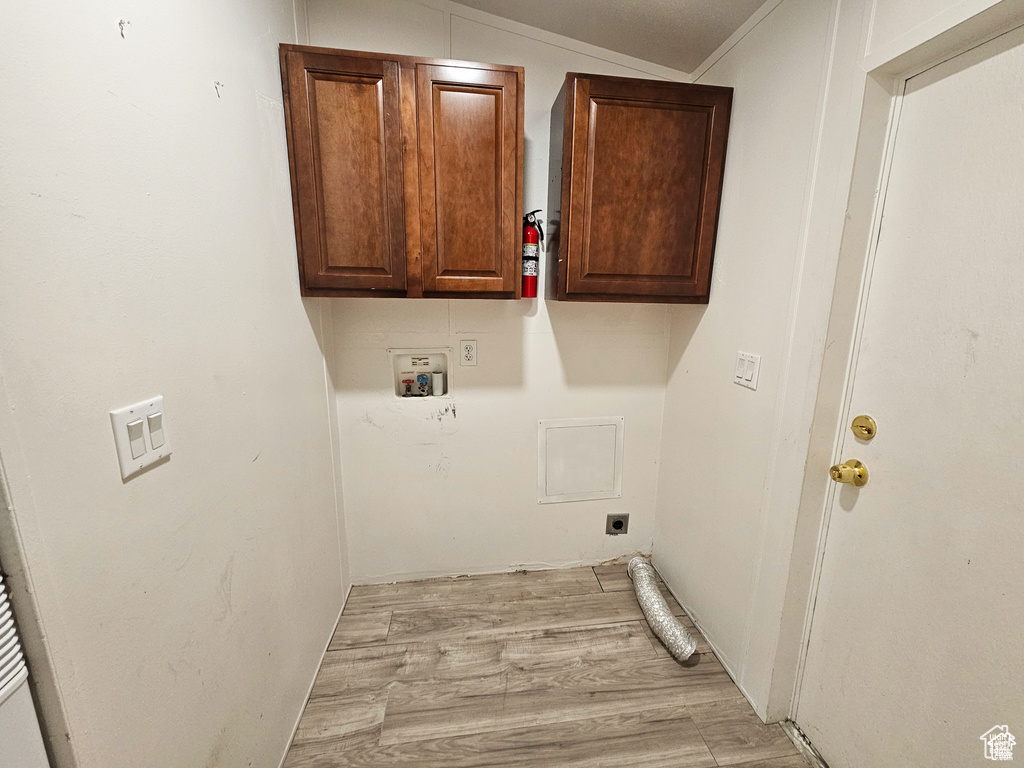 Clothes washing area with cabinets, hookup for a washing machine, light wood-type flooring, and electric dryer hookup