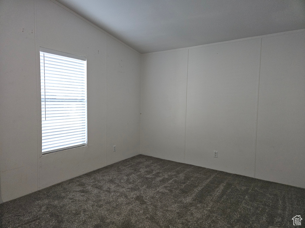 Carpeted empty room featuring vaulted ceiling