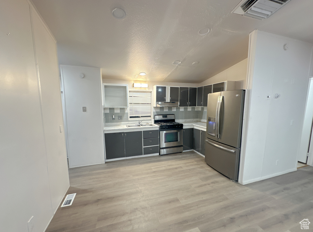 Kitchen with backsplash, light hardwood / wood-style floors, and appliances with stainless steel finishes