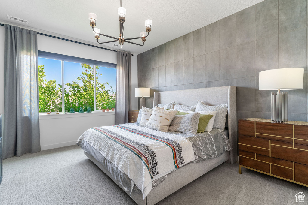 Bedroom with an inviting chandelier, light carpet, and tile walls