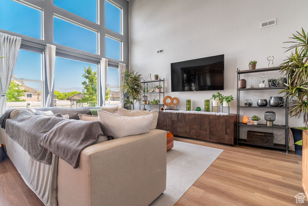 Living room with a high ceiling, light wood-type flooring, and a wealth of natural light