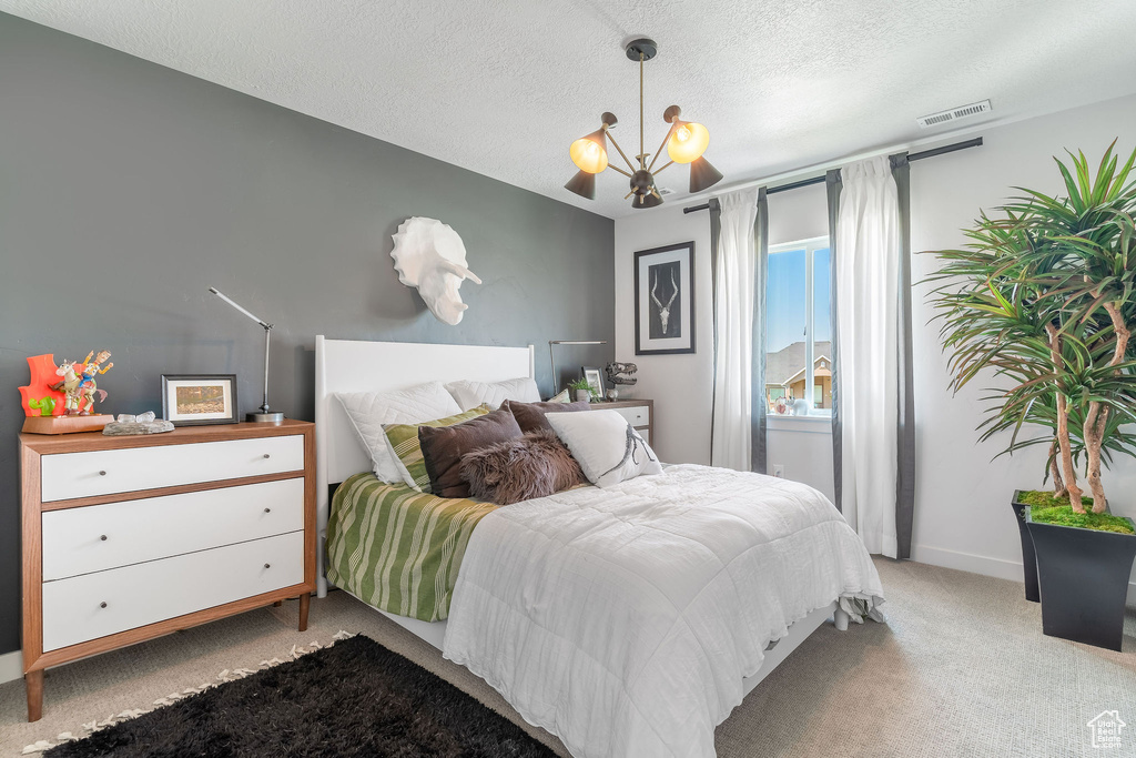 Carpeted bedroom with a textured ceiling and an inviting chandelier