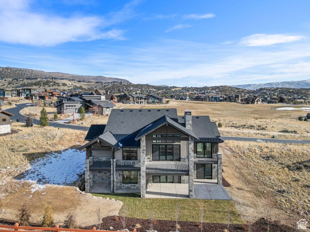 Rear view of property with stone siding, a patio, and a mountain view