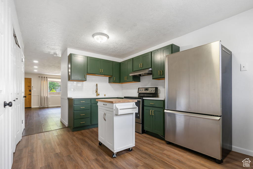 Kitchen with hardwood / wood-style flooring, stainless steel appliances, green cabinets, and a kitchen island