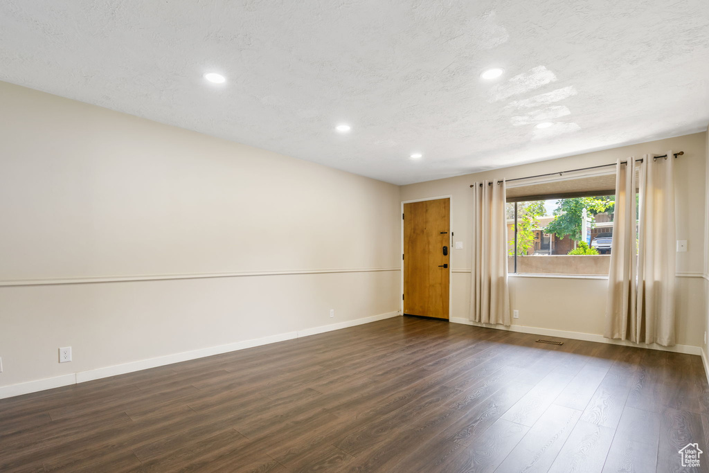 Unfurnished room with dark hardwood / wood-style floors and a textured ceiling