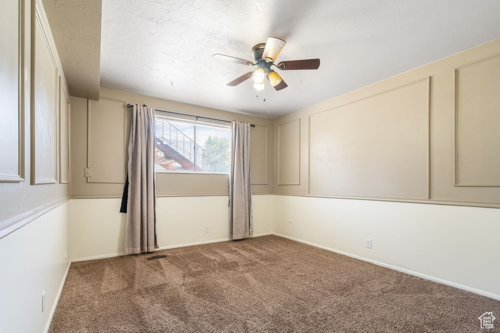 Carpeted empty room featuring ceiling fan