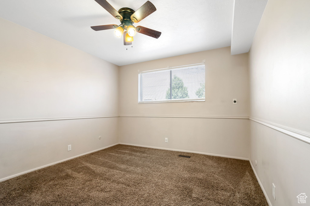 Spare room featuring carpet and ceiling fan