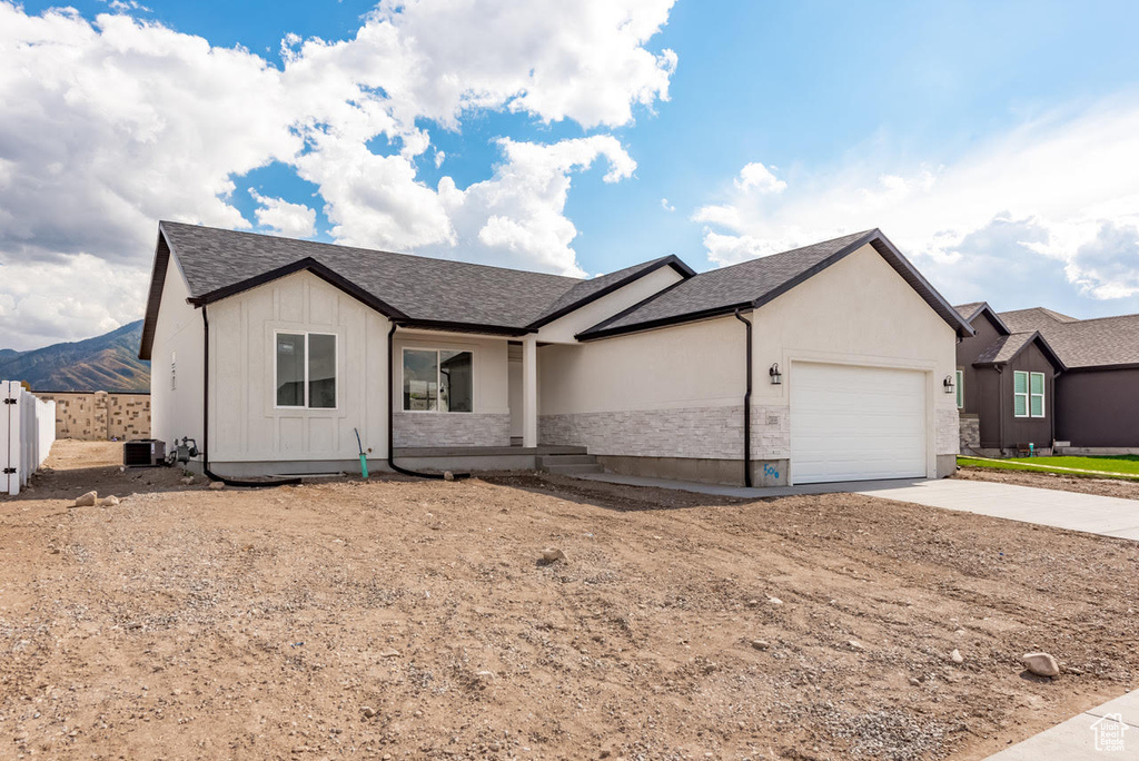 Single story home featuring central air condition unit and a garage