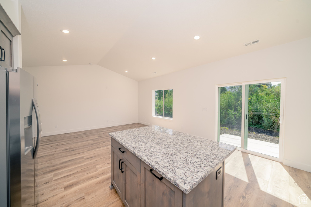 Kitchen with a center island, light hardwood / wood-style flooring, lofted ceiling, and stainless steel fridge with ice dispenser