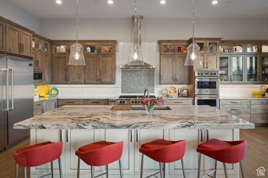 Kitchen with decorative backsplash, built in appliances, a sink, and recessed lighting