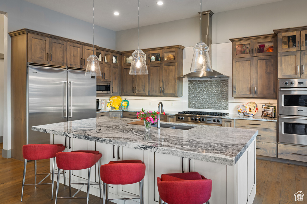 Kitchen with light stone counters, built in appliances, and backsplash