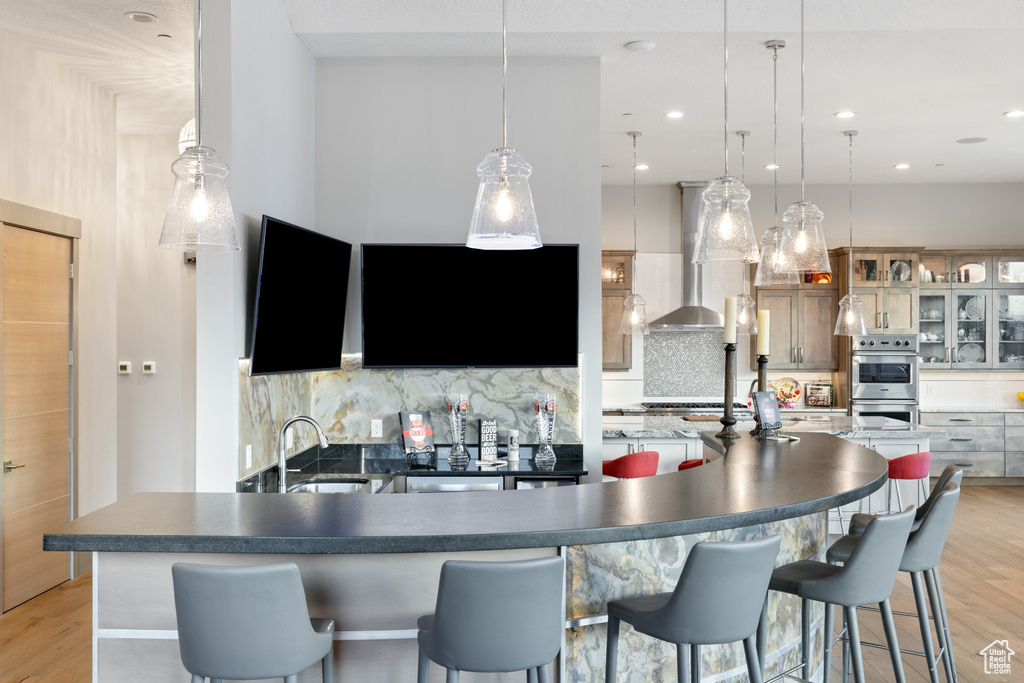 Kitchen featuring appliances with stainless steel finishes, a sink, wall chimney exhaust hood, and backsplash