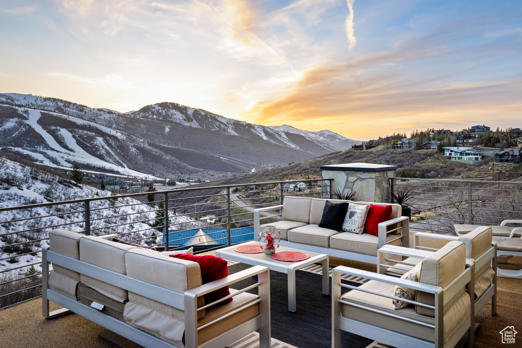 Snow covered patio with outdoor lounge area, a mountain view, and a balcony