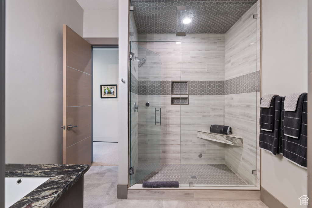 Bathroom featuring a stall shower, vanity, and tile patterned flooring