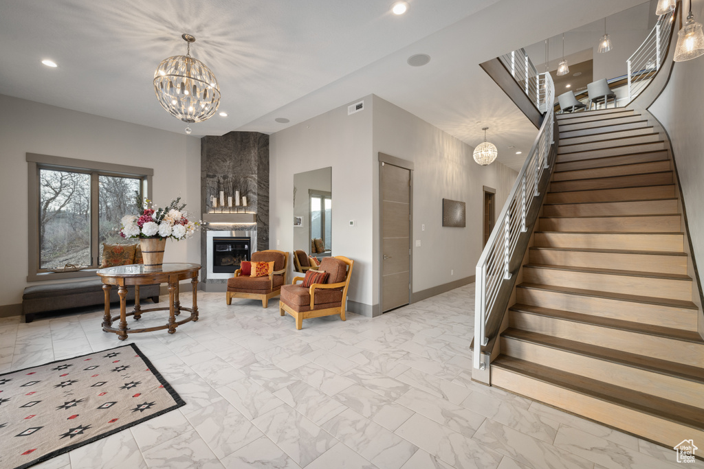 Living area with a notable chandelier, a large fireplace, recessed lighting, stairs, and marble finish floor