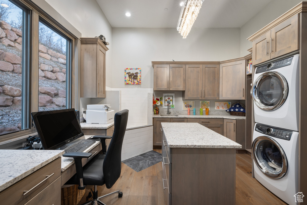 Washroom with dark wood-style flooring, stacked washer and clothes dryer, a chandelier, recessed lighting, and laundry area