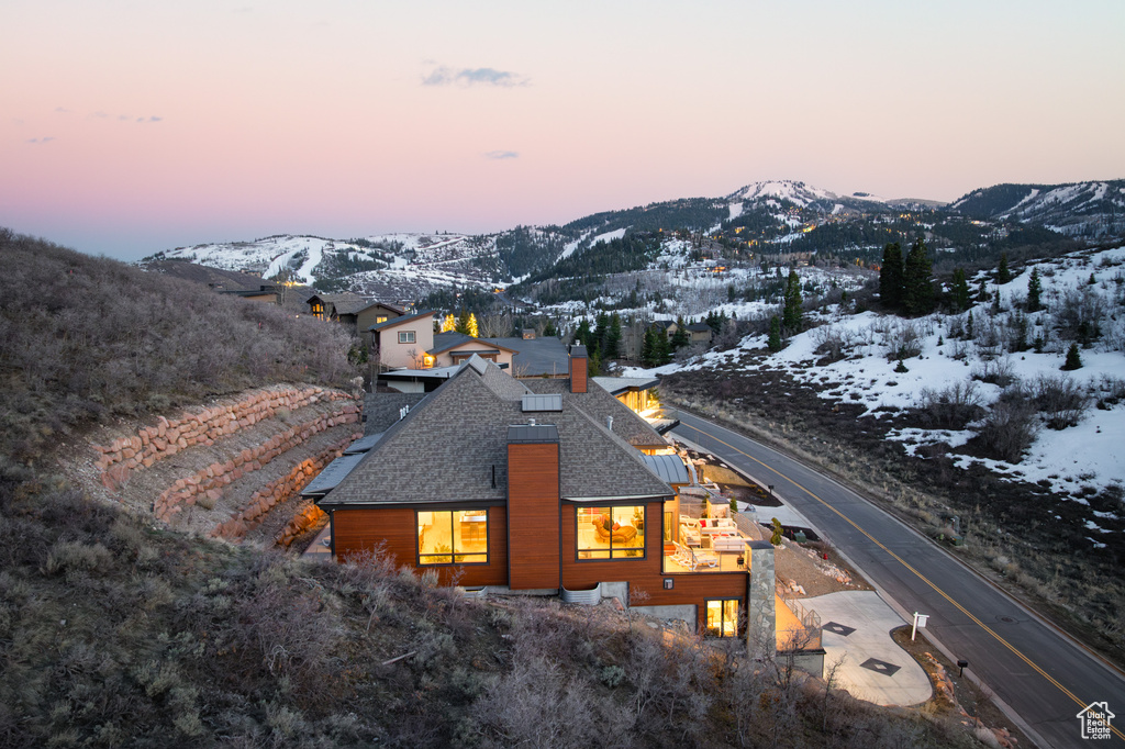 Snow covered back of property featuring a mountain view and a chimney