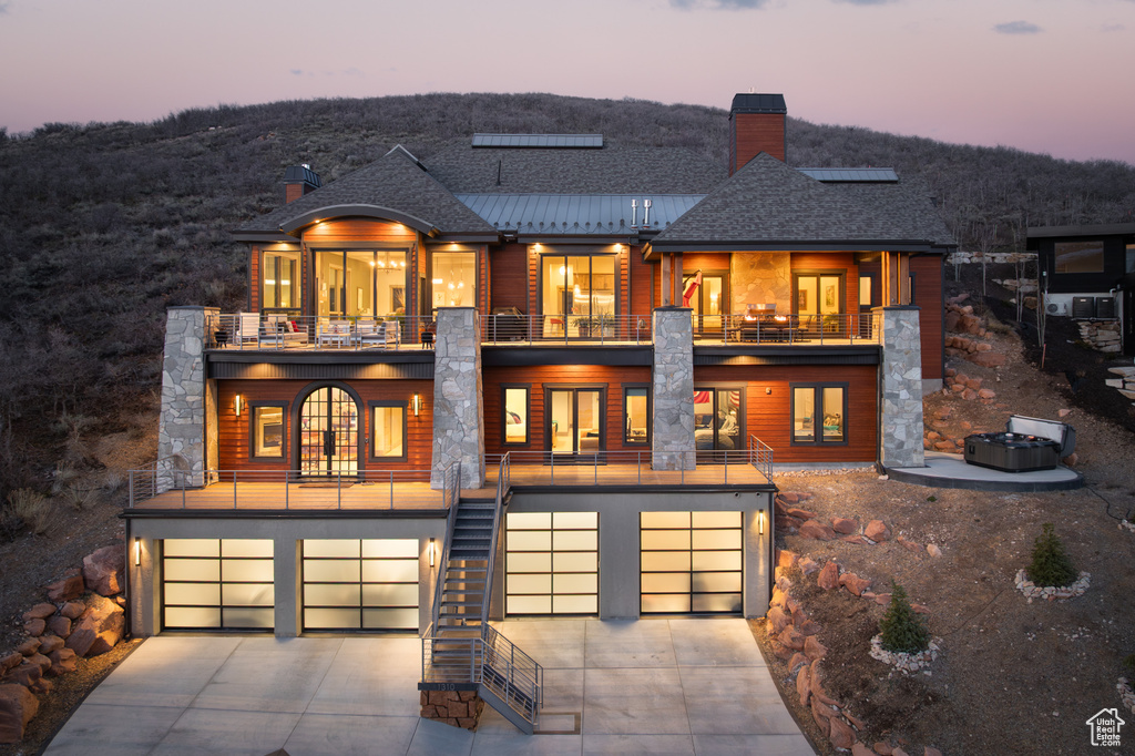 Exterior space with concrete driveway, a balcony, stairs, a garage, and a shingled roof