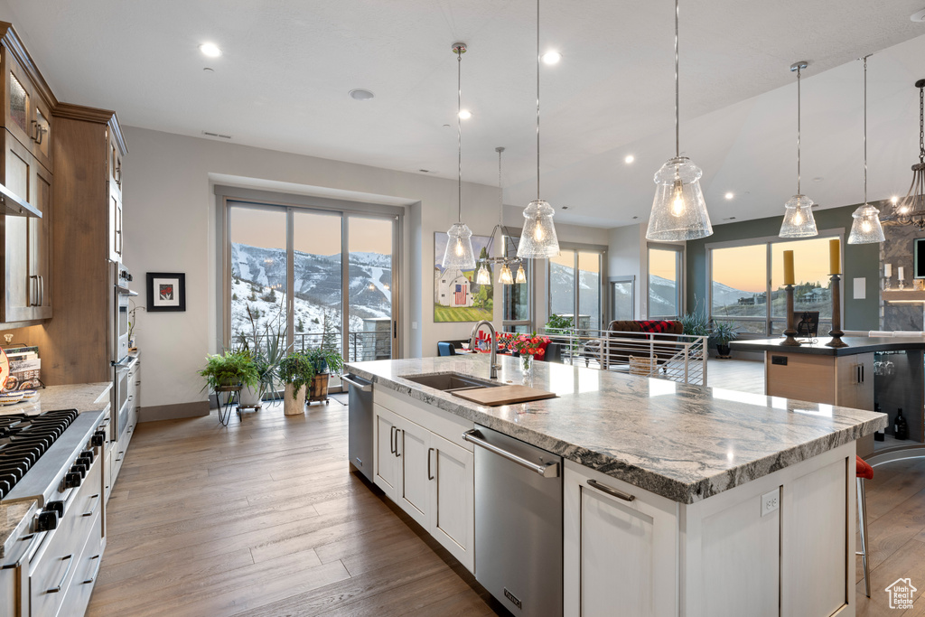 Kitchen with a mountain view, light stone countertops, a center island with sink, stainless steel appliances, and a sink