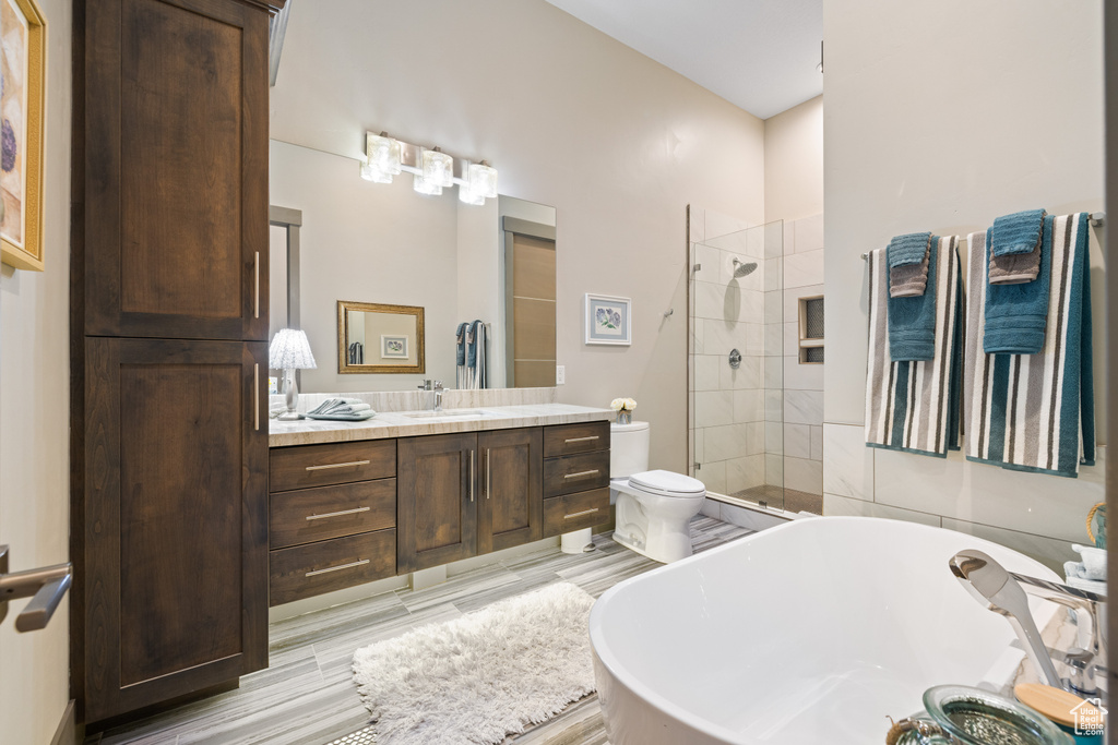 Full bathroom with vanity, a soaking tub, toilet, tiled shower, and wood finished floors