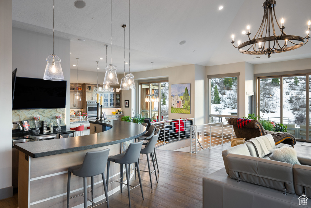 Interior space featuring a notable chandelier, a sink, open floor plan, dark countertops, and dark wood-style floors
