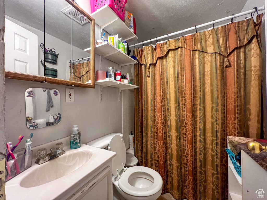 Bathroom featuring vanity, a textured ceiling, and toilet