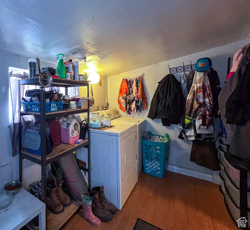 Laundry room featuring a textured ceiling, washer and clothes dryer, and wood-type flooring