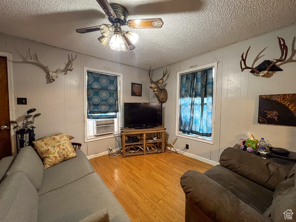 Living room with a textured ceiling, ceiling fan, hardwood / wood-style floors, and cooling unit