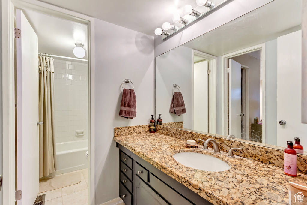 Bathroom featuring shower / bathtub combination with curtain, vanity, and tile patterned floors