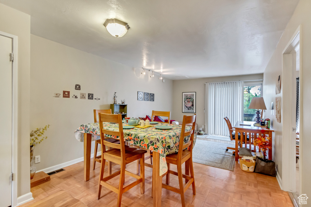 Dining space featuring light parquet floors and track lighting