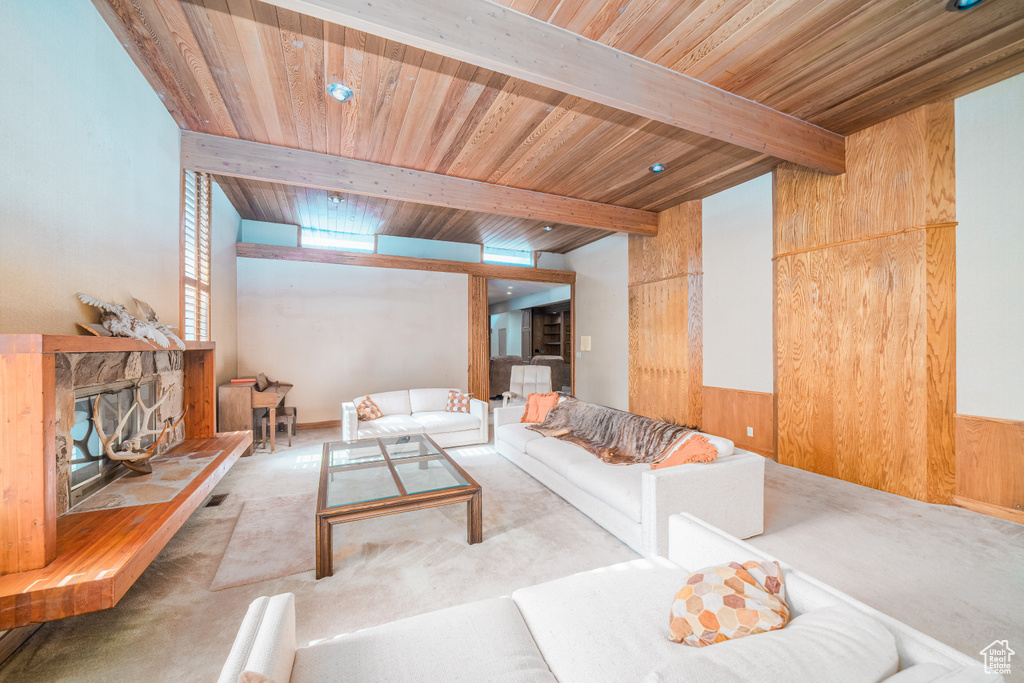 Carpeted living room featuring a fireplace, beamed ceiling, and wood ceiling