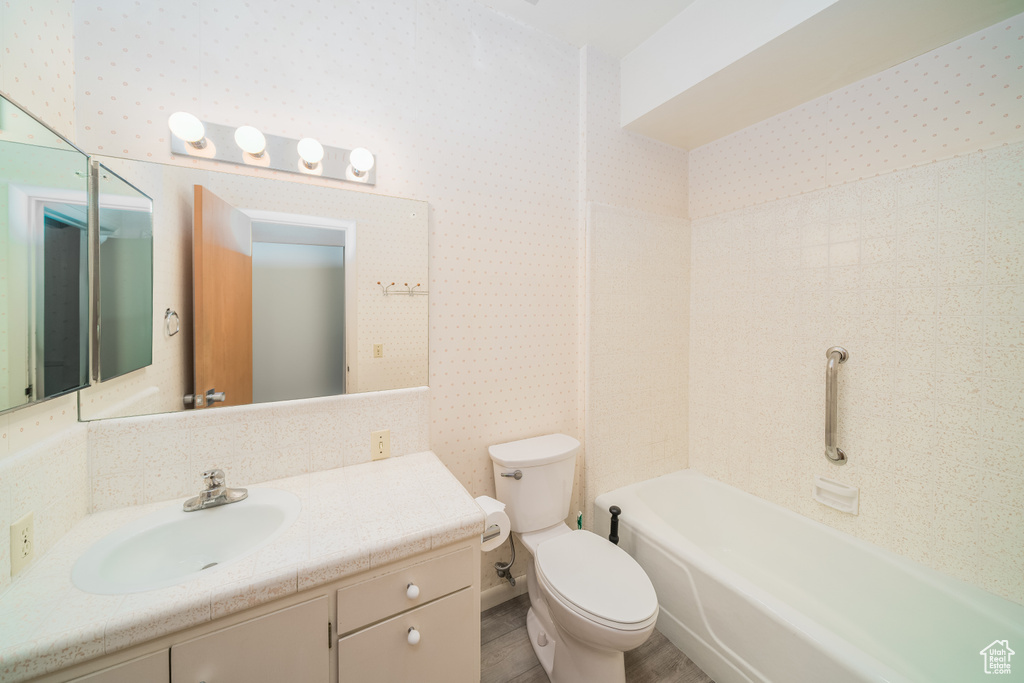 Full bathroom featuring vanity, tiled shower / bath combo, and toilet